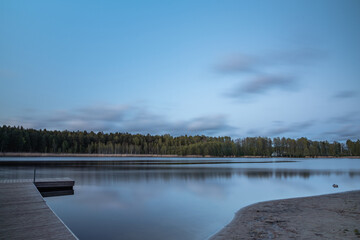 Wooden pier on the forest lake on spring . Long exposure.
