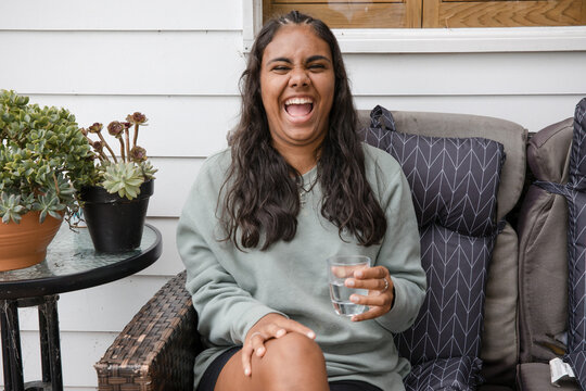Young Aboriginal woman sitting on a couch outside laughing