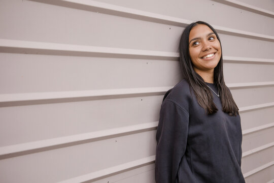 Portrait of a young, smiling,  first nations woman against wall outside