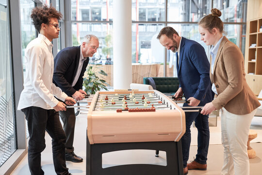 Business Leute am Kickertisch beim Tischfu&szlig;ball spielen