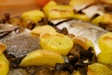 oven grilled sea bream fish with delicious curry sauce served on baking tray, baked potatoes with...