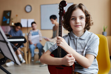 Portrait of little boy with musical instrument looking at camera while studying in music class
