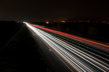 Fototapeta na wymiar Cars light trails on a straight highway at sunset. Night traffic trails, Motion blur, Night city road with traffic headlight motion. 