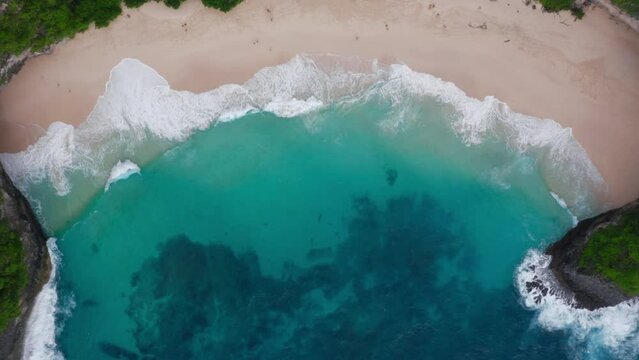 Aerial top view of ocean waves rolling on white sand beach in tropical paradise. Wild seaside with people. Turquoise lagoon and White Sea wash. Idyllic natural background. Copter footage. Paradise
