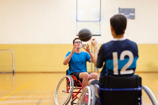 two young men practising passing for wheelchair basketball
