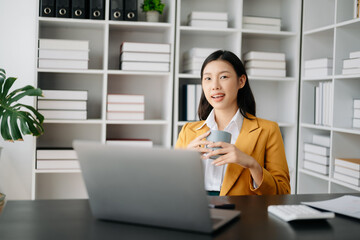 Young attractive Asian female office worker business suits smiling at camera in modern office .