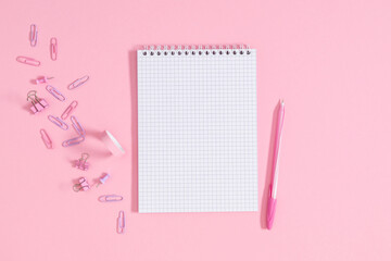 Back to school concept. Flat lay top view of scattered stationery notepad pens pencils paper clips  sticky tape note paper isolated on pastel pink background 