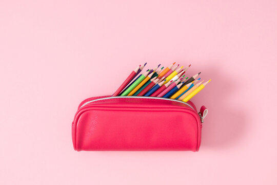 Back to school concept. Flat lay top view on pink full pencil case with pencils and pens isolated on pastel pink background