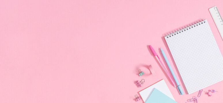 Back to school concept. Flat lay top view of scattered stationery notepad pens pencils paper clips  sticky tape note paper isolated on pastel pink background banner - Powered by Adobe