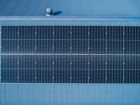 Row of solar panels on tin roof seen from aerial view