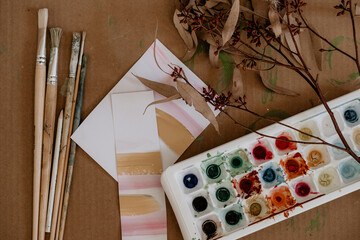 Paint brushes and paints with brush strokes on paper.