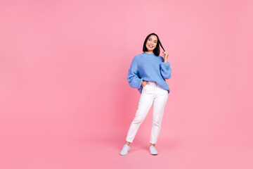 Full size photo of gorgeous woman dressed knit pullover trousers look at sale empty space arm in pocket isolated on pink color background