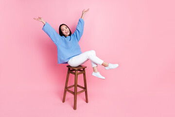 Full length photo of gorgeous pretty girl blue sweater white pants sitting on bar stool raising...
