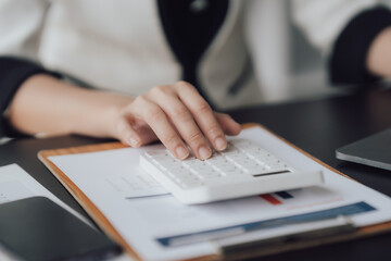 businessman or accountant hand working on calculator to calculate business data, accounting document and laptop computer at office, business concept