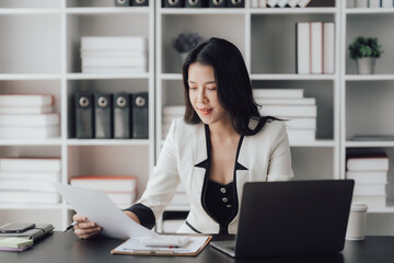 Obraz na płótnie Canvas Cheerful business lady working on laptop in office, Asian happy beautiful businesswoman in formal suit work in workplace. Attractive female employee office worker smile.