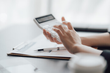 businessman or accountant hand working on calculator to calculate business data, accounting document and laptop computer at office, business concept