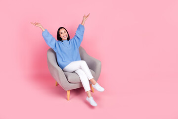 Full body photo of cheerful nice lady sit chair raise arms empty space ad isolated on pink color background