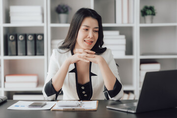 Cheerful business lady working on laptop in office, Asian happy beautiful businesswoman in formal suit work in workplace. Attractive female employee office worker smile.