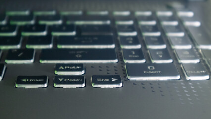 Laptop arrow keys with illumination and blurred background. Gaming powerful grey notebook keyboard close-up. Tech, IT, electronics, computer science background