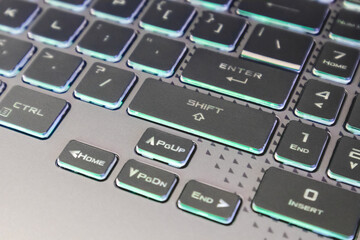 Arrow keys with illumination and selective focus. Gaming powerful grey notebook keyboard close-up. Tech, IT, electronics, computer science background