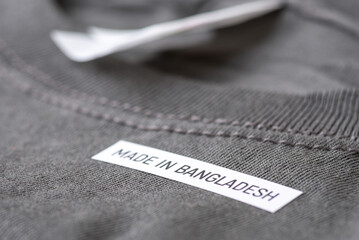 Black T-Shirt with words Made in Bangladesh, close up. Production of clothes in South Asia, cheep,...