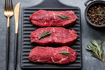 Fresh meat. Raw beef steaks with rosemary and spices on a stylish blackboard. Flat top view.