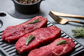 Fresh meat. Raw beef steaks with rosemary and spices on a stylish blackboard. Flat top view.
