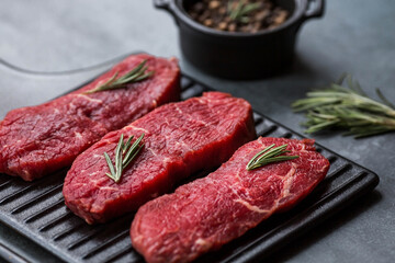 Fresh meat. Raw beef steaks with rosemary and spices on a stylish blackboard. Flat top view.