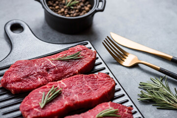 Fresh meat. Raw beef steaks with rosemary and spices on a stylish blackboard. Flat top view.