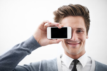 It has a great camera. A young nerdy guy holding his smartphone against his eye.