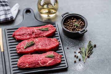 Fresh meat. Raw beef steaks with rosemary and spices on a stylish blackboard. Flat top view.