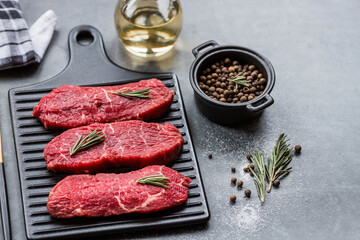 Fresh meat. Raw beef steaks with rosemary and spices on a stylish blackboard. Flat top view.