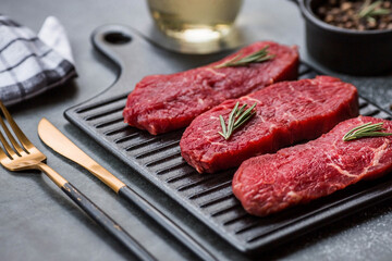 Fresh meat. Raw beef steaks with rosemary and spices on a stylish blackboard. Flat top view.