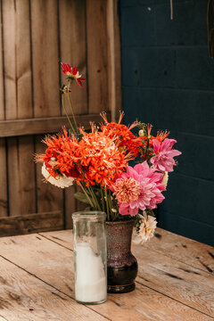 Vase of dahlias on a table with a rustic candle.