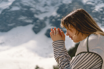 Woman closed her eyes, praying near the mountain. Hands folded in prayer concept for faith, spirituality and religion. Peace, hope, dreams concept