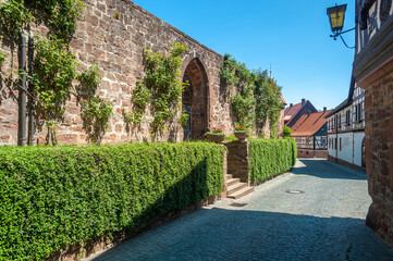 Fototapeta na wymiar Gasse in der Altstadt von Dörrenbach mit Befestigung der historischen Wehrkirche. Region Pfalz im Bundesland Rheinland-Pfalz in Deutschland