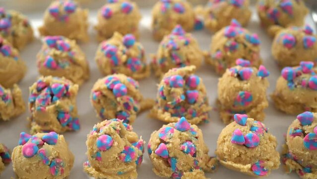 Chilled cookie dough scoops on the baking sheet to bake unicorn chocolate chip cookies.