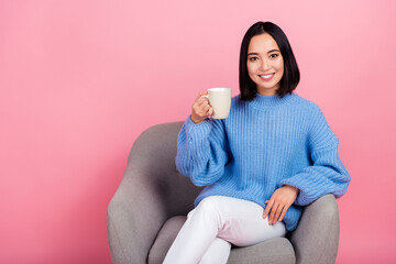 Photo of cheerful nice person sit chair hand hold fresh coffee cup empty space isolated on pink color background