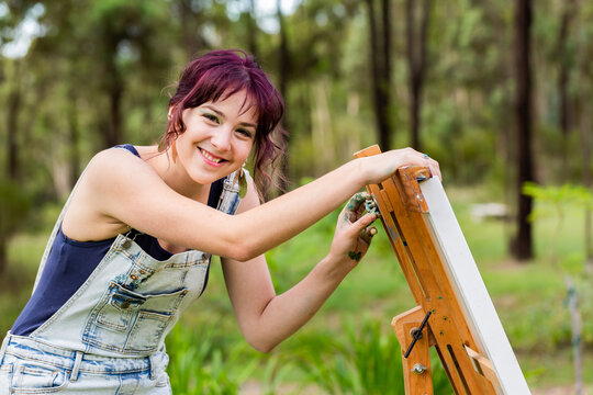 Young artist adjusting height of painting easel