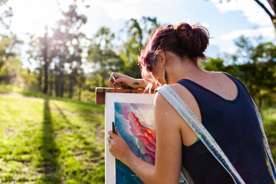 Young artist in overalls painting art outside in nature
