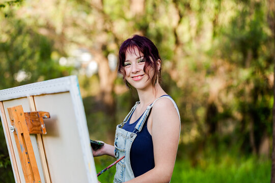 Self taught young artist working on canvas painting outside