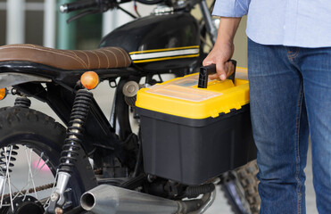 Mechanic holding a toolbox to service a motorcycle workshop.