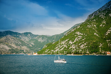 View of famous Bay of Kotor and a floating white yacht towards Our Lady of the Rocks
