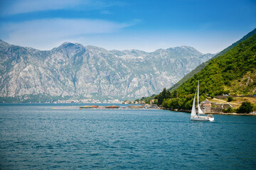 View of famous Bay of Kotor and a floating white yacht on a beautiful sunny day