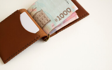 Brown leather money clip, purse with ukrainian hryvnia banknotes. Men's genuine leather wallet. Accessories. Money, financess, economy, saving.