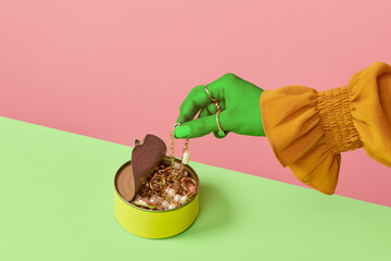 Portrait of female hands opening jewelry box and putting on accessories over pink studio background. Trash pop art, bright colors. Dressing up