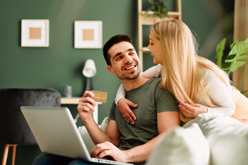 Young happy couple shopping via laptop online at home