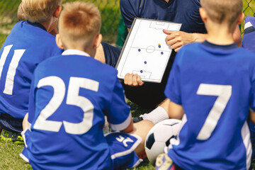 Coaching Kids in Youth Sports. Group of Young Boys Sitting Together With Coach in a Circle on the...