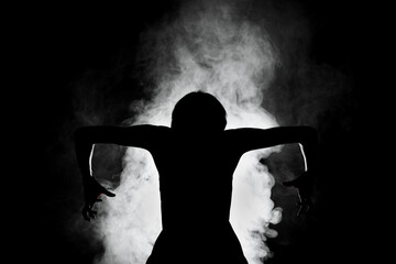silhouette modern ballet dancer posing on dark background with smoke