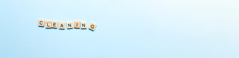 Banner The word cleaning made of wooden letters. Flat lay cleaning from letters on blue background